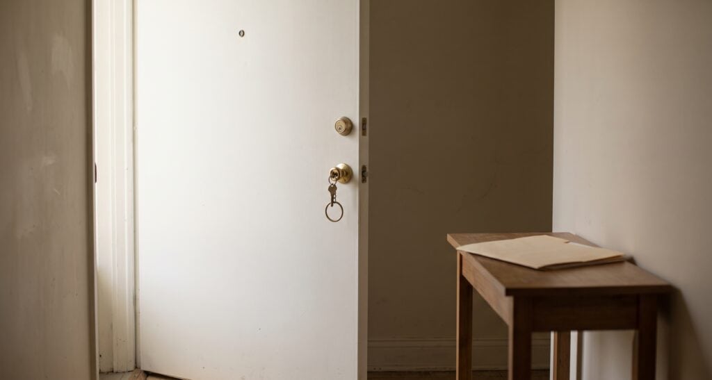 Florida's New Rental Application Fraud Felony: What HB 1293 Says A brass key resting in the lock of a plain apartment door with a folder of papers on a table nearby